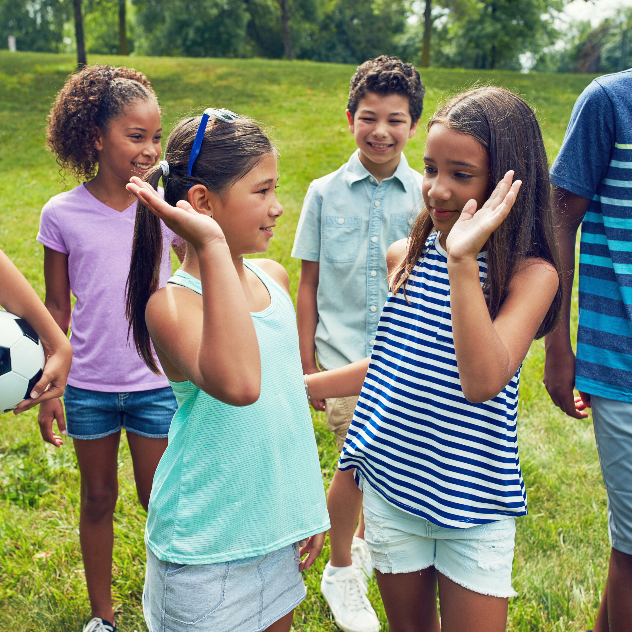 Girl, children and high five with friends at park for game, holiday and happy for soccer in summer. Kids, group and excited for support, motivation and smile on field, break or fun at playground